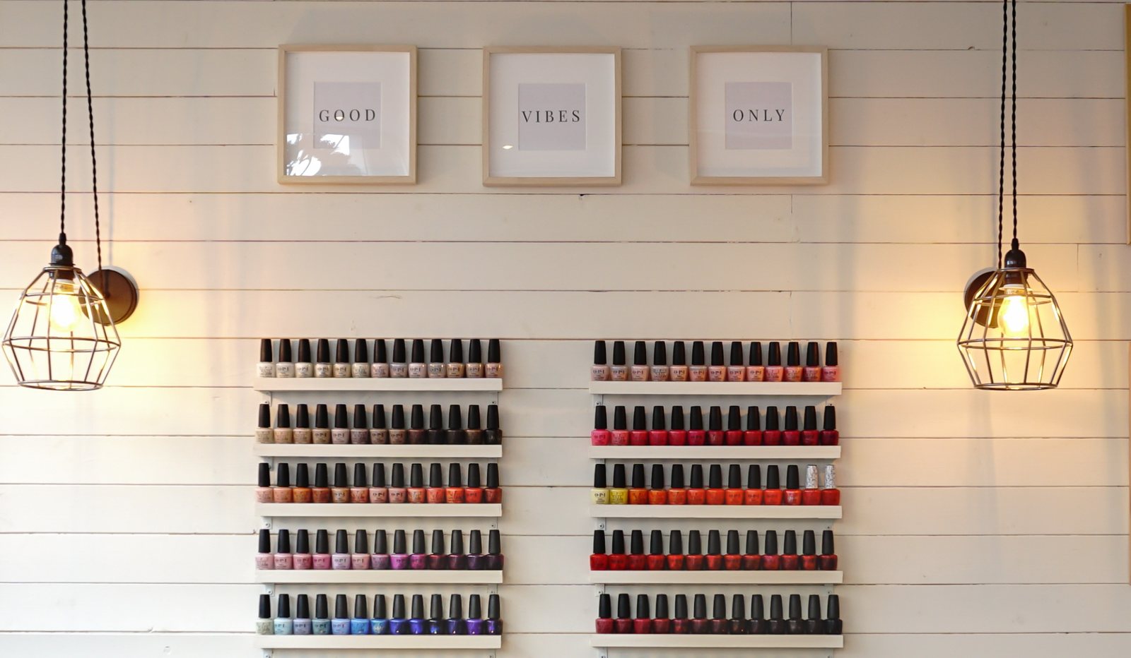 Rows of nail polish beneath "Good Vibes Only" prints at House Cats